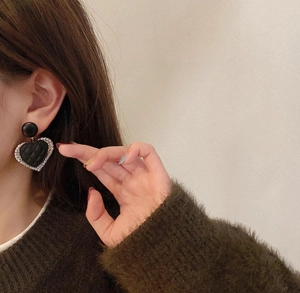 Detail of heart-shaped black quilted leather earrings with sparkling rhinestones