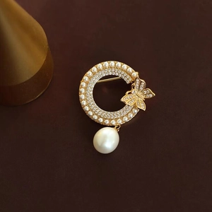 Broche papillon dorée élégante avec perles et strass sur un fond sombre minimaliste