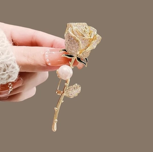Broche élégante en rose dorée avec strass brillants et une grande perle blanche