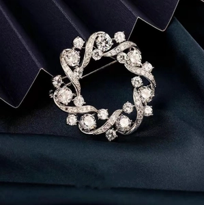 Elegant silver circular wreath brooch with sparkling white zircons on deep blue silk
