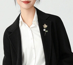 Elegant gold rose brooch with pearl and green leaf on black blazer lapel for luxury styling
