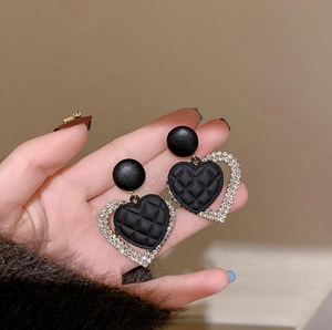 Macro shot of heart-shaped earrings with quilted black leather and rhinestones