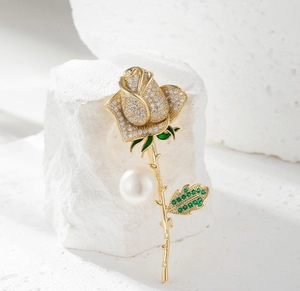 Detail of rose brooch with white zircons, green gemstones and a large white pearl