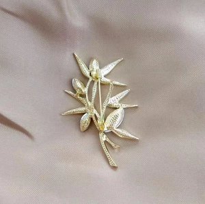 Close-up of gold bamboo brooch back showing secure pin clasp and textured metal finish