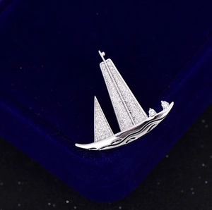 Détail de la broche voilier avec cristaux pavés étincelants et finition argentée