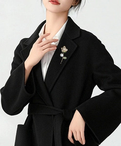 Elegant rose brooch with white pearls and crystals pinned on a stylish black wool coat