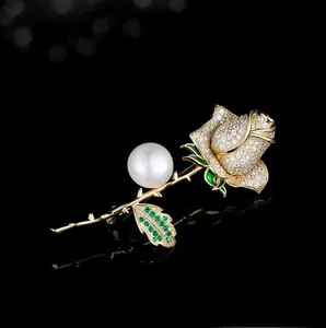 Detail of rose flower brooch with white zircons, green stones and a large pearl
