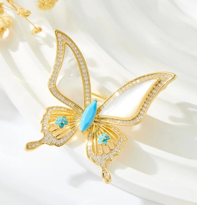 Détail de la broche papillon avec cadre doré, pierres bleues et nacre blanche élégante