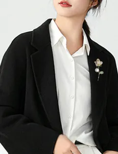 Detail of elegant gold rose brooch with sparkling crystals and a white pearl on clothing