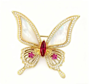 Détail de broche papillon avec ailes en nacre, centre en gemme rouge et fleurs roses