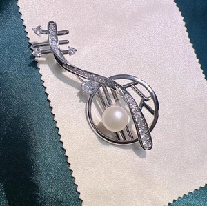 Elegante spilla pipa d'argento con perla e zirconi su uno sfondo di seta verde
