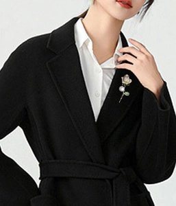 Elegant rose brooch with white rhinestones and a pearl on a black wool coat