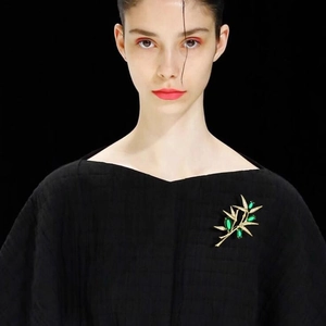 Luxurious gold bamboo brooch with green gemstones on a black blazer lapel