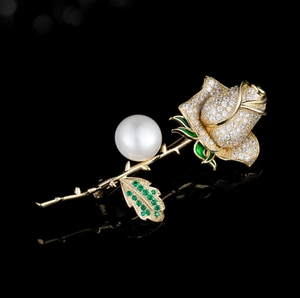 Elegant rose brooch with golden finish, zircon petals and pearl center on black background
