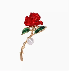Détail d'une broche rose rouge émaillée avec feuilles vertes et perle blanche