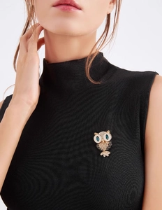 Close-up of owl brooch featuring crystal pave inlay and deep blue gemstone eyes