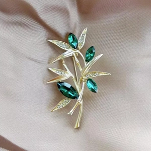 Elegant green bamboo brooch in gold plating with crystal accents on champagne silk