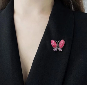 Detailed close-up of a mini butterfly brooch with purple rhinestones on a black suit lapel