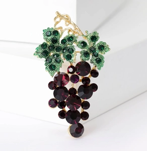 Detailed close-up of a golden grape brooch with green rhinestones and purple crystals