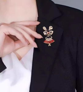 Détail d'une broche lapin avec strass rouges sur le revers d'un tailleur sombre