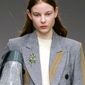 Luxury bamboo brooch with green gems on a grey wool blazer, elegant suit accessory