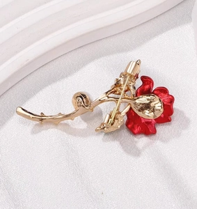 Vue arrière détaillée de la broche rose rouge montrant l'épingle dorée et le fermoir