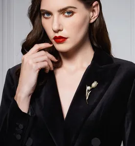 Detailed view of elegant gold tulip brooch with pearl on black velvet suit lapel