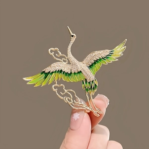 Detail of elegant crane brooch with green enamel wings and sparkling rhinestones