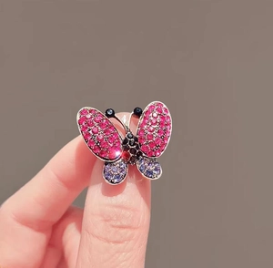 Macro shot of mini butterfly brooch with pink and purple rhinestones on a golden base