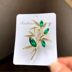 Exquisite golden bamboo brooch featuring green marquise gemstones and white rhinestones