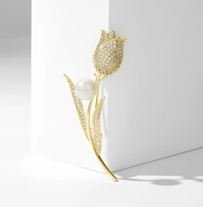 Detailed view of golden tulip brooch with white zircon petals and a large center pearl
