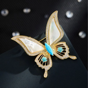 Broche papillon dorée avec des ailes en nacre et des pierres bleues sur du velours noir