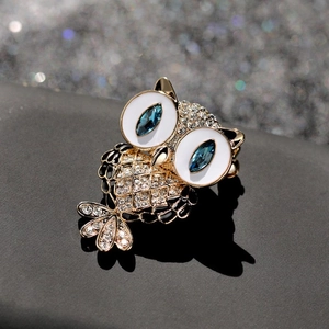 Exquisite owl brooch with gold base, blue gem eyes, and sparkling zircon crystals