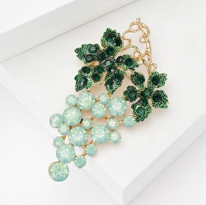 Close-up of elegant gold grape brooch with emerald green crystals and mint gemstones