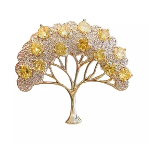 Dettaglio spilla albero della vita dorata con zirconi gialli e trasparenti incastonati