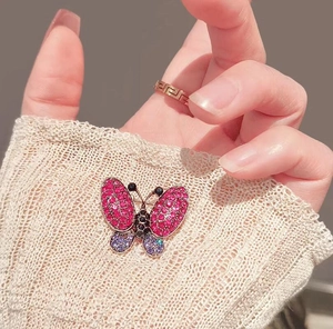 Detailed macro view of a butterfly brooch with purple rhinestones on a white knit sleeve