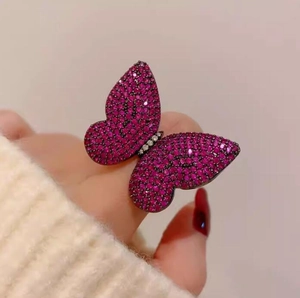 Luxury butterfly ring with pink pavé stones and white diamonds on a soft knit background