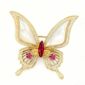 Broche papillon dorée élégante avec ailes en nacre et accents de cristaux rouges