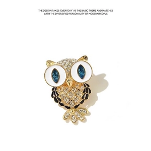 Elegant owl brooch with gold plating, sparkling rhinestones, and blue gem eyes on white base