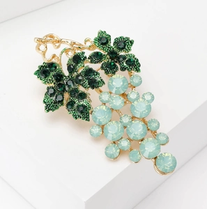 Detailed view of elegant grape brooch featuring green rhinestones and blue crystals