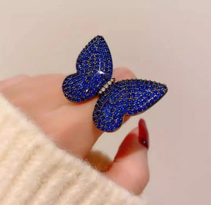 Detailed close-up of a large luxury blue butterfly brooch worn on a white sweater