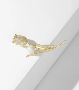 Detailed view of elegant gold tulip brooch featuring pavé diamonds and a round pearl