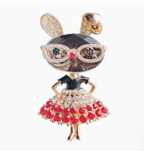Détail d'une broche de dessin animé avec cristal noir et jupe ornée de strass rouges