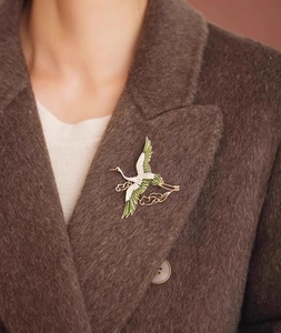 Detailed close-up of an elegant crane brooch with auspicious clouds on a wool coat lapel