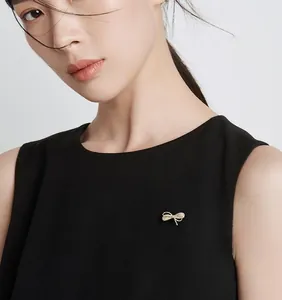 Broche nœud dorée exquise avec strass blancs sur le revers d'une robe noire