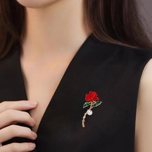 Elegant red enamel rose brooch with green leaves and a pearl on a model's jacket