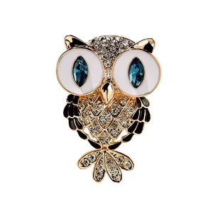 Elegant owl brooch with gold base, sparkling clear crystals, and blue gemstone eyes