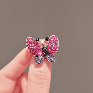 Exquisite butterfly brooch with purple rhinestones worn on finger to show delicate size