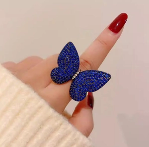 Detailed close-up of a vintage butterfly ring with dark blue crystals on a finger