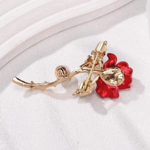 Elegant red rose brooch with gold metal base and red enamel petals on white silk backdrop